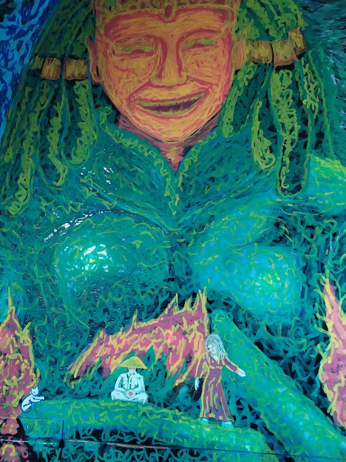 Une immense divinité verte au visage souriant, au-dessus de deux petits personnages, dont l'un médite.